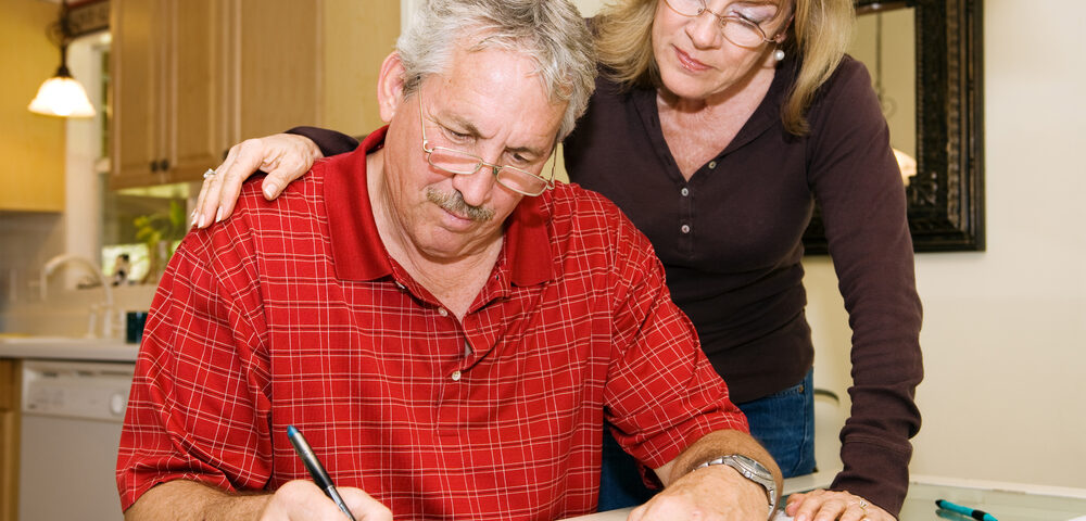 Mature couple in financial trouble is filling out a loan application.