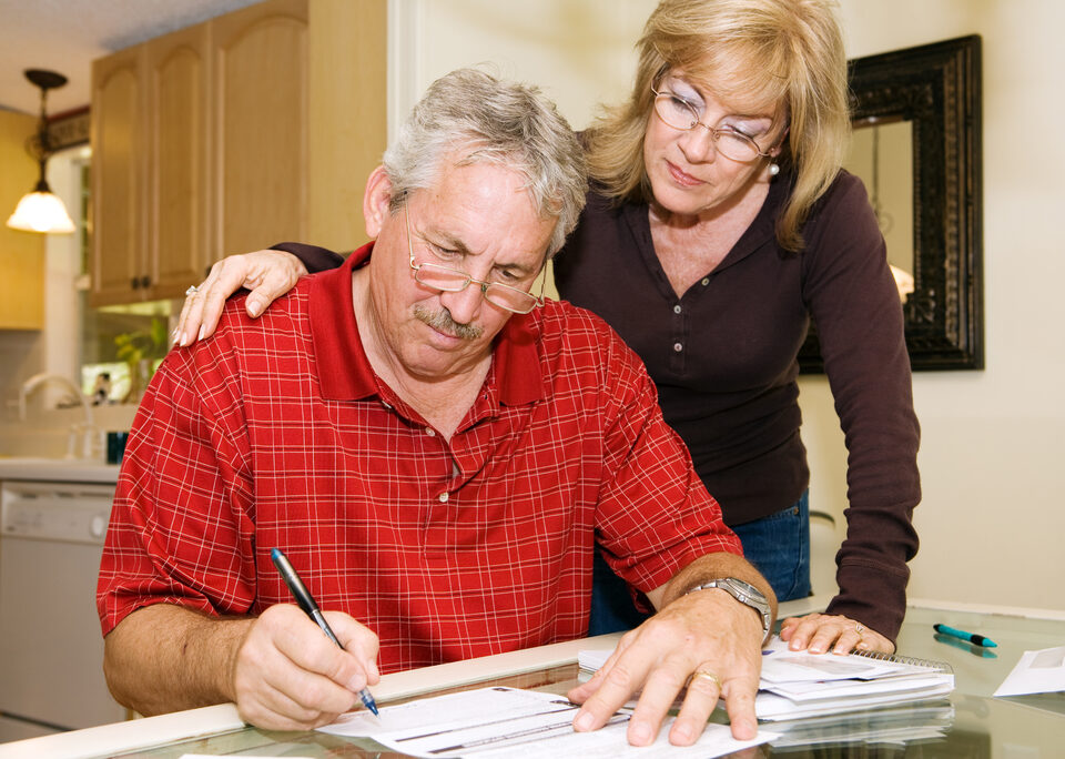 Mature couple in financial trouble is filling out a loan application.