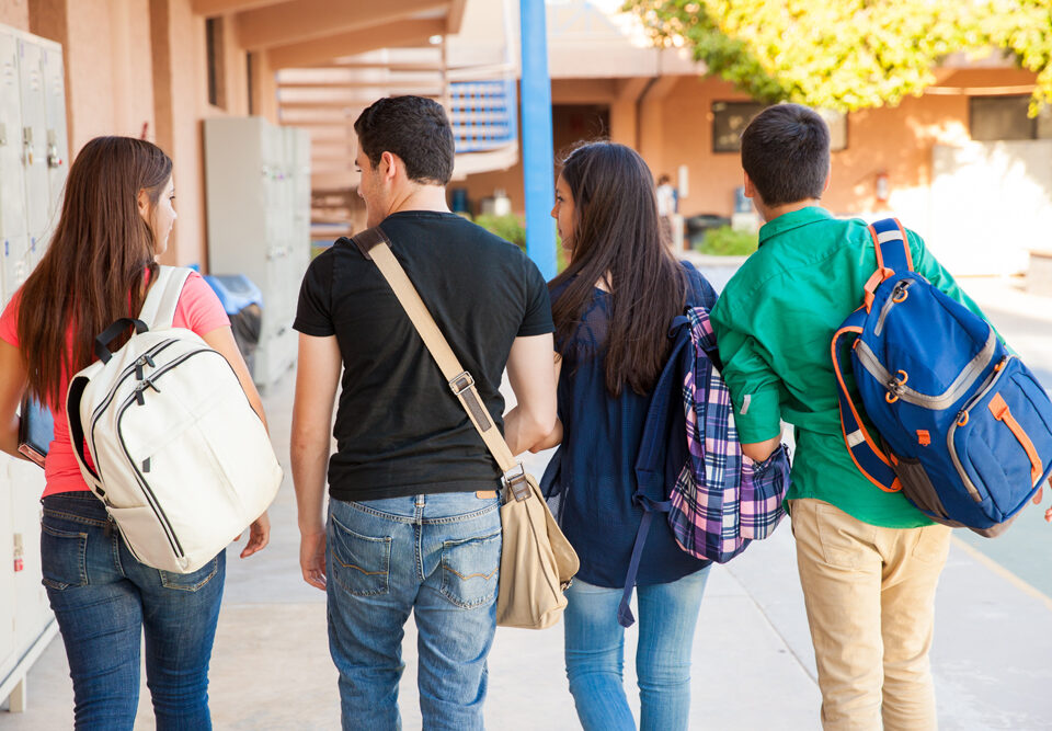 Rear view of a bunch of high school students walking down the hallway