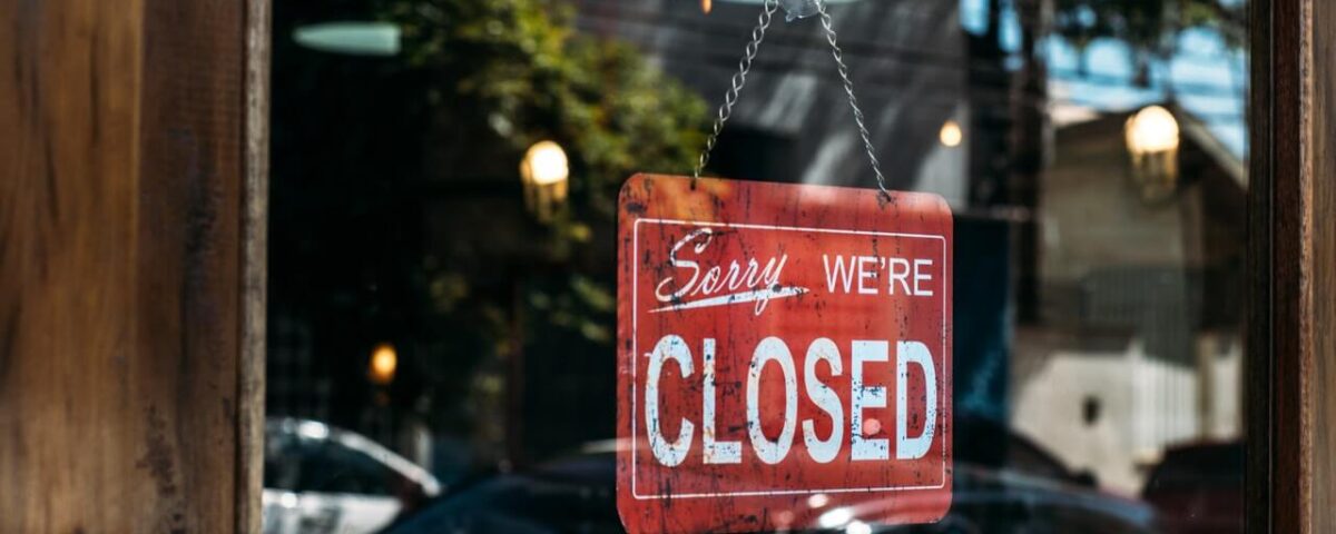 wood and glass door with a red "sorry, we're closed" sign hanging on the glass.