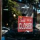 wood and glass door with a red "sorry, we're closed" sign hanging on the glass.