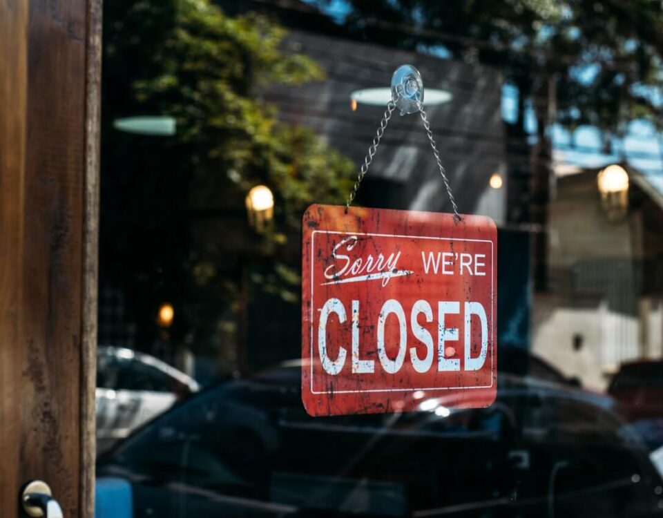 wood and glass door with a red "sorry, we're closed" sign hanging on the glass.