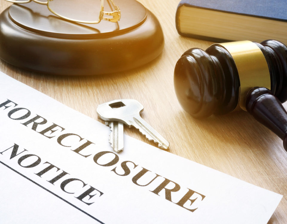 brown and gold gavel lying on a desk with gavel rest. 2 silver keys laying near a foreclosure notice