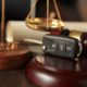 justice scales, brown and gold gavel in background with a car key fob sitting on a wooden gavel rest.