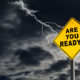 "Are You Ready" road sign against a dark, stormy sky with lightening streaking